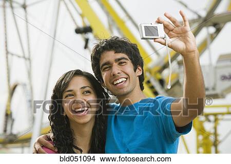 Picture - Ethnic-ethnic teenaged couple taking own photograph. Fotosearch