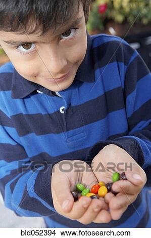 Picture - Hispanic boy holding handful of candy. Fotosearch