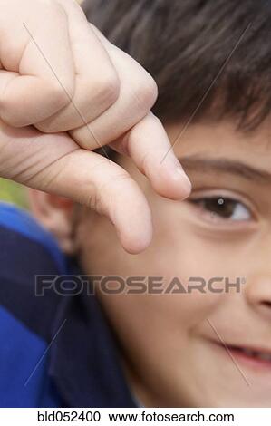 Stock Image - Hispanic boy holding out thumb and forefinger. Fotosearch