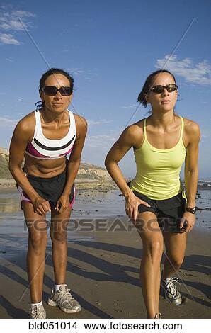 Picture - Hispanic female runners racing at beach. Fotosearch