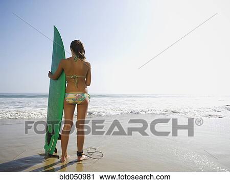 Stock Image - Hispanic girl holding surfboard. Fotosearch