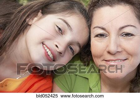 Stock Photography - Hispanic girl leaning on mother’s shoulder. Fotosearch
