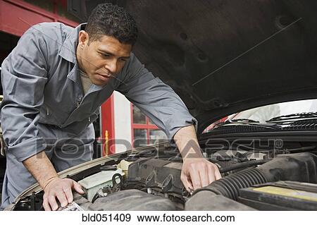 Stock Photo - Hispanic male auto mechanic under hood of car. Fotosearch
