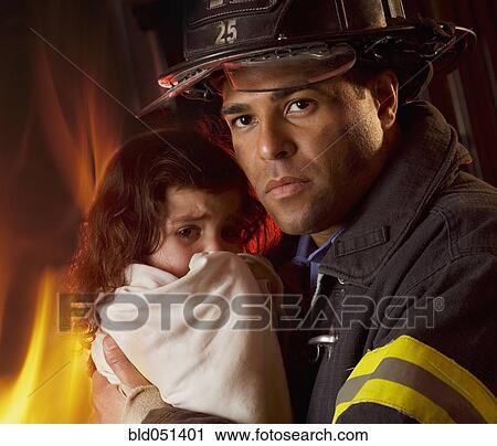 Stock Image - Hispanic male firefighter holding child. Fotosearch
