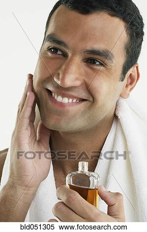 Stock Photography - Hispanic man applying cologne. Fotosearch