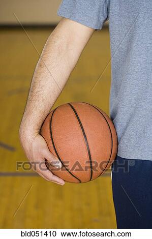 Stock Image - Hispanic man holding basketball. Fotosearch