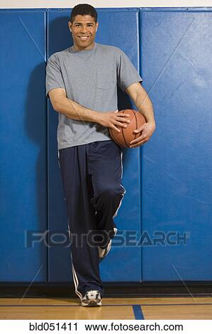 Stock Image - Hispanic man holding basketball. Fotosearch