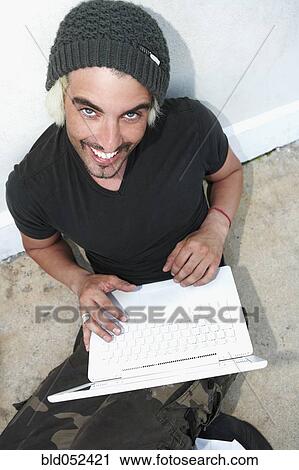 Stock Image - Hispanic man holding laptop. Fotosearch