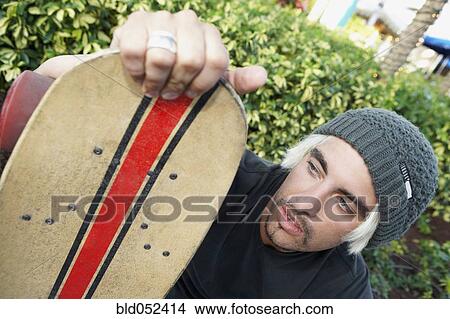 Hispanic man holding skateboard View Large Photo Image Picture - Hispanic man holding skateboard. Fotosearch