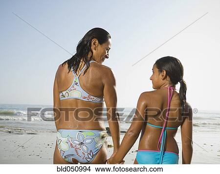 Picture - Hispanic mother and daughter holding hands. Fotosearch