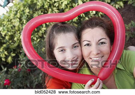 Hispanic mother and daughter holding heart-shaped balloon View Large Photo Image Stock Photo - Hispanic mother and daughter holding heart-shaped balloon. Fotosearch