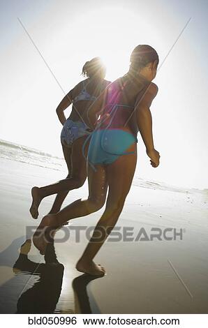Stock Photograph - Hispanic mother and daughter running at beach. Fotosearch