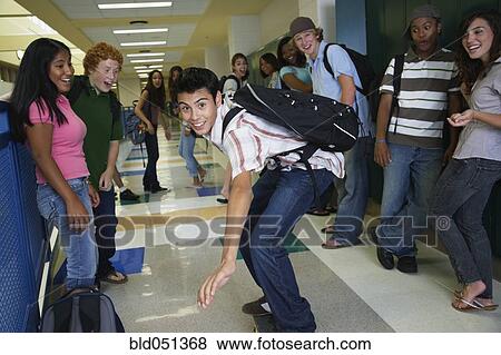 Stock Photo - Hispanic teenaged boy riding skateboard in school hallway. Fotosearch