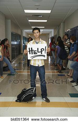 Picture - Hispanic teenaged student holding Help sign. Fotosearch