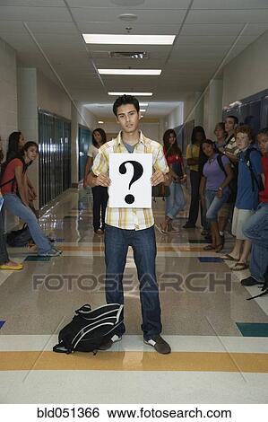 Stock Photograph - Hispanic teenaged student holding question mark sign. Fotosearch
