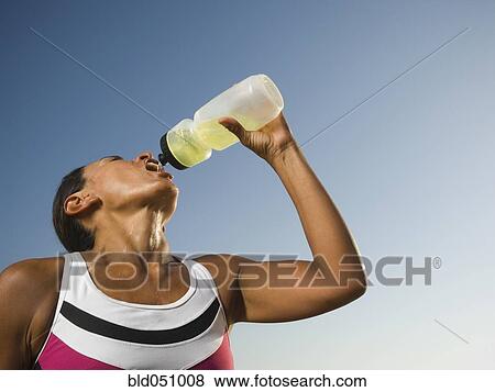 Hispanic woman drinking from squeeze bottle View Large Photo Image Stock Photo - Hispanic woman drinking from squeeze bottle. Fotosearch