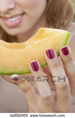 Stock Photography - Hispanic woman eating melon slice. Fotosearch