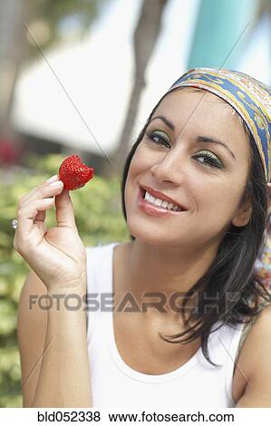 Stock Photo - Hispanic woman eating strawberry. Fotosearch