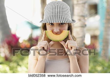 Stock Photo - Hispanic woman holding melon slice. Fotosearch