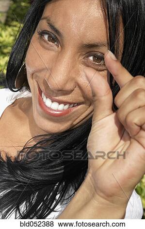 Stock Photo - Hispanic woman holding out thumb and index finger. Fotosearch