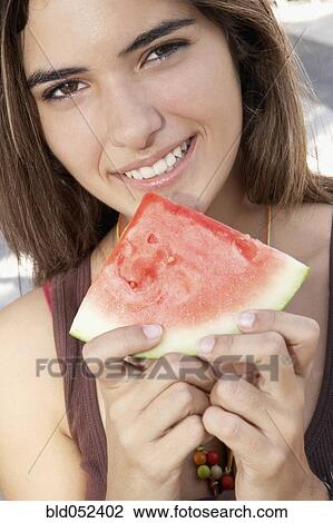 Stock Image - Hispanic woman holding watermelon slice. Fotosearch