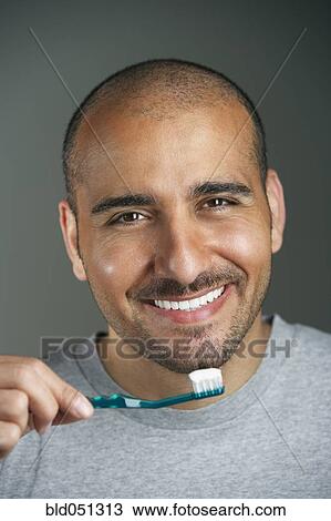 Stock Image - Middle Eastern man brushing teeth. Fotosearch