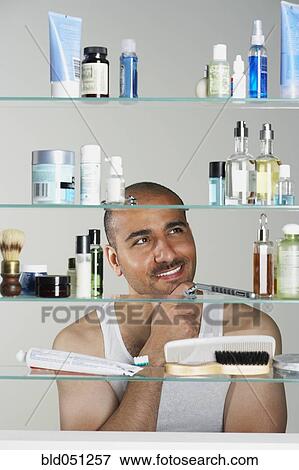 Middle Eastern man looking in medicine cabinet View Large Photo Image Stock Photo - Middle Eastern man looking in medicine cabinet. Fotosearch