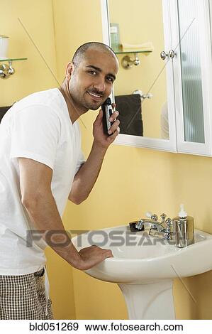 Stock Photo - Middle Eastern man shaving with electric razor. Fotosearch