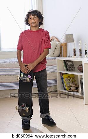 Picture - Mixed Race boy holding skateboard. Fotosearch
