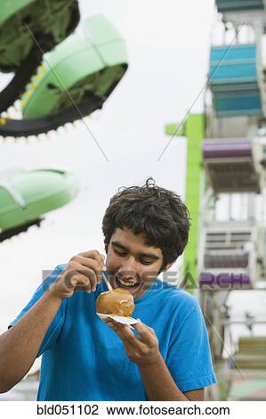 Mixed Race teenaged boy eating candied apple View Large Photo Image Stock Image - Mixed Race teenaged boy eating candied apple. Fotosearch