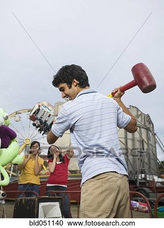 Stock Image - Mixed Race teenaged boy playing carnival game . Fotosearch