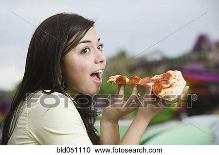 Stock Image - Mixed Race teenaged girl eating pizza. Fotosearch
