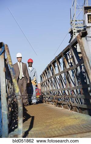 Multi-ethnic businessman and construction worker walking View Large Photo Image Stock Image - Multi-ethnic businessman and construction worker walking. Fotosearch