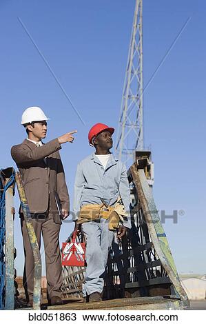 Multi-ethnic businessman and construction worker walking View Large Photo Image Stock Image - Multi-ethnic businessman and construction worker walking. Fotosearch
