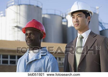 Multi-ethnic businessman and construction worker wearing hardhats View Large Photo Image Stock Image - Multi-ethnic businessman and construction worker wearing hardhats. Fotosearch
