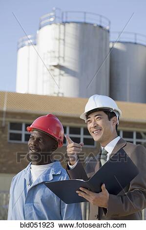 Multi-ethnic businessman and construction worker pointing View Large Photo Image Stock Image - Multi-ethnic businessman and construction worker pointing. Fotosearch