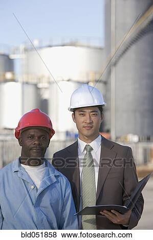 Stock Photo - Multi-ethnic businessman and construction worker wearing hardhats. Fotosearch
