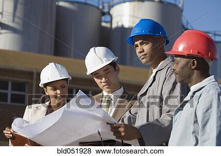 Stock Photo - Multi-ethnic businesspeople and construction workers looking at blueprints. Fotosearch