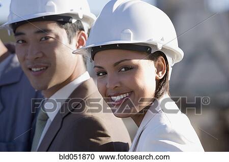 Stock Image - Multi-ethnic businesspeople wearing hardhats. Fotosearch