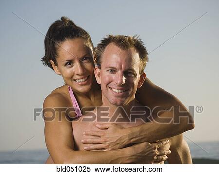 Stock Photography - Multi-ethnic couple hugging at beach. Fotosearch