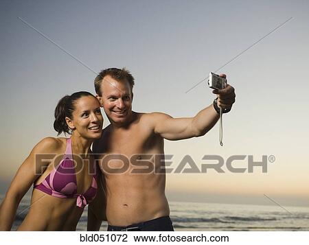 Stock Image - Multi-ethnic couple taking own photograph. Fotosearch
