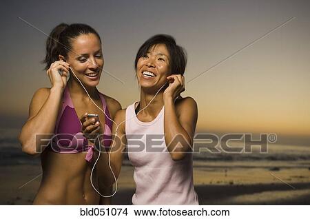 Multi-ethnic friends listening to same mp3 player View Large Photo Image Picture - Multi-ethnic friends listening to same mp3 player. Fotosearch