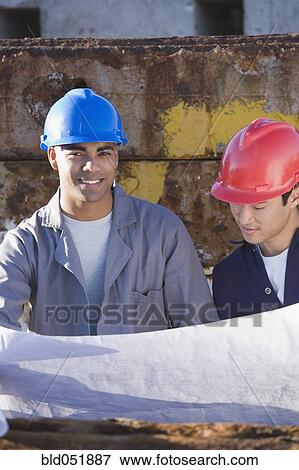 Multi-ethnic male construction workers holding blueprints View Large Photo Image Stock Photo - Multi-ethnic male construction workers holding blueprints. Fotosearch