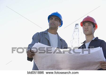 Multi-ethnic male construction workers holding blueprints View Large Photo Image Stock Photograph - Multi-ethnic male construction workers holding blueprints. Fotosearch