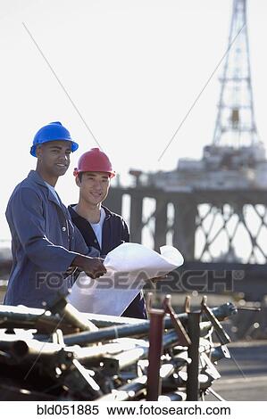 Multi-ethnic male construction workers holding blueprints View Large Photo Image Stock Photography - Multi-ethnic male construction workers holding blueprints. Fotosearch