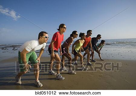 Stock Image - Multi-ethnic runners racing at beach. Fotosearch