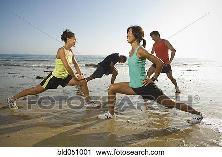 Stock Image - Multi-ethnic runners stretching at beach. Fotosearch