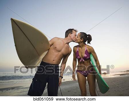 Stock Photo - Multi-ethnic surfer couple kissing. Fotosearch