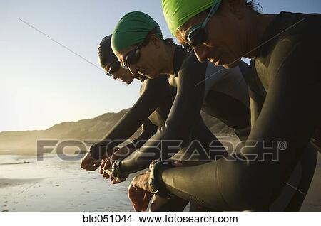 Multi-ethnic swimmers checking watches View Large Photo Image Picture - Multi-ethnic swimmers checking watches. Fotosearch