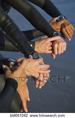 Stock Image - Multi-ethnic swimmers checking watches. Fotosearch